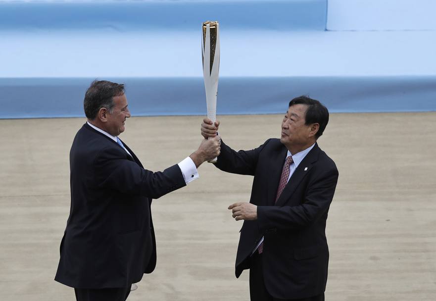 Il capo del comitato olimpico greco passa la torcia olimpica al presidente del comitato organizzatore sudcoreano Lee Hee-beom. Ap